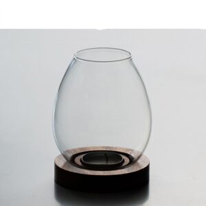 Portacandele in vetro trasparente a forma di uovo su base rotonda scura, con un tealight nell’incavo
