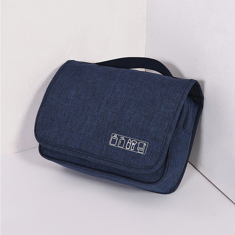 Beauty case blu scuro chiuso, appoggiato a un angolo, con maniglia